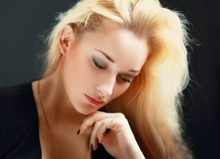 Young thoughtful female looking down over dark background