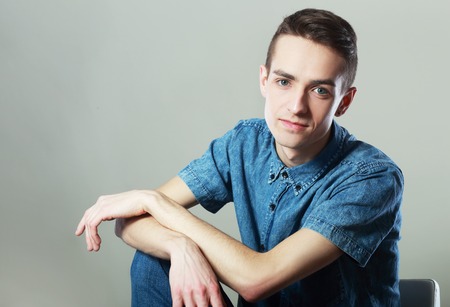 Portrait of young man in black shirt sitting on chairの写真素材