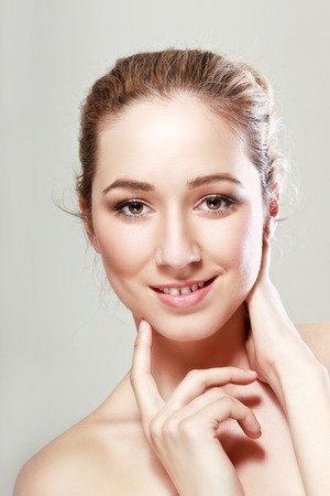close up portrait of beautiful young woman with hands near her chin on neutral backgroundの写真素材