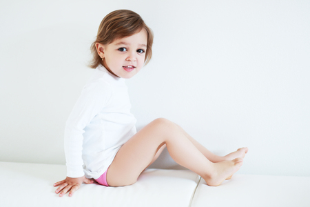 Adorable 2 year old girl sitting barefoot at homeの写真素材