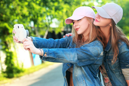Two happy teenage girls sister or friends in hipster outfit (jeans shorts