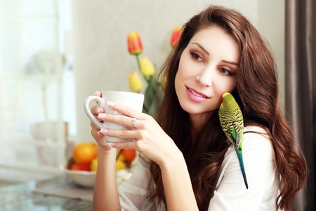 beautiful smiling woman with green parrot on her shoulderの写真素材