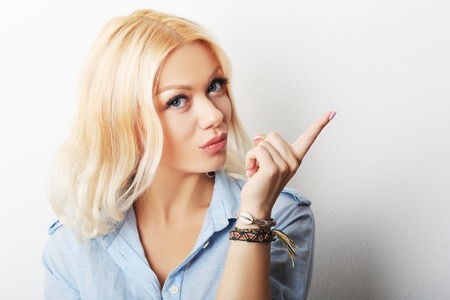 Beautiful young woman pointing to somewhere, isolated over a white backgroundの写真素材