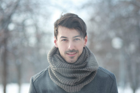 Outdoor portrait of smiling handsome man in coat and scurf. Casual winter fashion