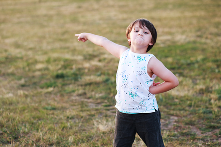 6 years old boy pointing to copyspace with serious making face outdoorの写真素材