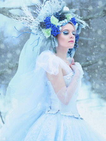 beautiful winter fairy in crown and light blue dress walking over snow field Snow Queen conceptの写真素材