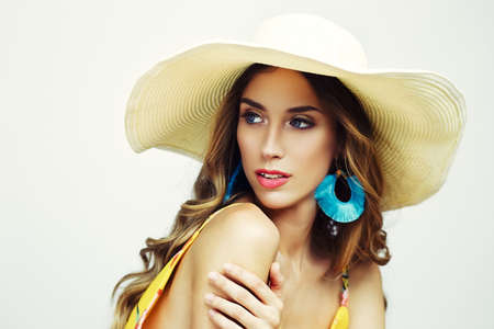 beautiful young woman wearing summer hat and turquoise earrings looking outside the pictureの写真素材