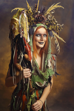 Shaman woman with creative face art fantasy make-up headpiece with floral elements and hornsの写真素材