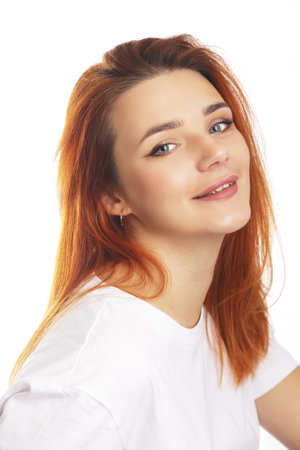 beautiful red haired woman smiling on camera wearing white shirt casualの写真素材