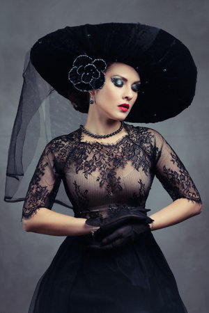 Femme fatale woman in black fashionable hat and lace dressの写真素材