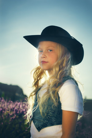 blond little girl outdoor in cowboy hat lavender on backgroundの写真素材