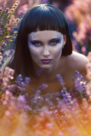 beautiful woman with creative make up dark mood in summer flower fieldの写真素材
