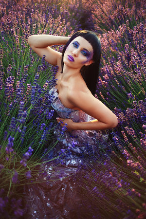 beautiful woman with creative make up dark mood in summer flower lavender fieldの写真素材