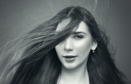 black and white portrait of a young woman long hair fly by windの写真素材