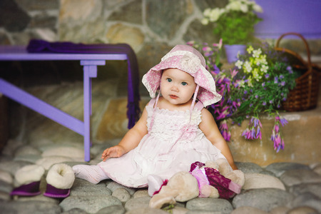 the child in a pink dress with a beads sits on stonesの写真素材