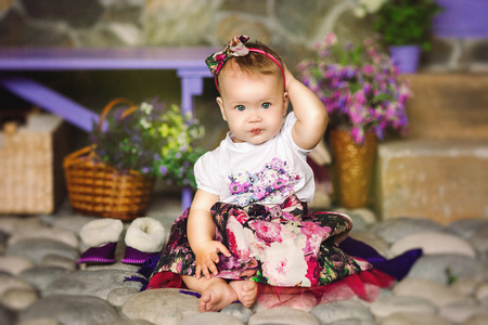 the child in a multi-colored dress with a beads sits on stonesの写真素材