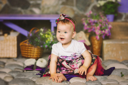the child in a multi-colored dress with a beads sits on stonesの写真素材