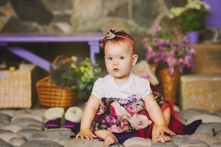 the child in a multi-colored dress with a beads sits on stonesの写真素材