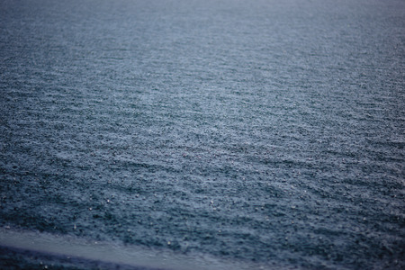 drops of a rain fall on a silent smooth surface of the lakeの写真素材