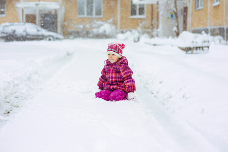 the girl in a lilac down-padded coat walks in snow weather on snowdriftsの写真素材