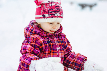 the girl in a lilac down-padded coat walks in snow weather on snowdriftsの写真素材