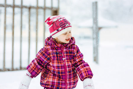 the girl in a lilac down-padded coat walks in snow weather on snowdriftsの写真素材