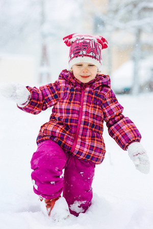 the girl in a lilac down-padded coat walks in snow weather on snowdriftsの写真素材