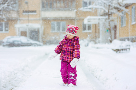 the girl in a lilac down-padded coat walks in snow weather on snowdriftsの写真素材
