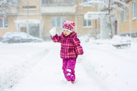the girl in a lilac down-padded coat walks in snow weather on snowdriftsの写真素材