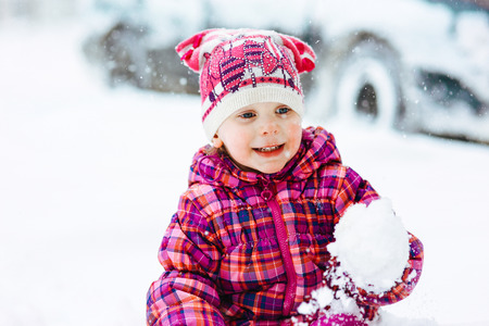 the girl in a lilac down-padded coat walks in snow weather on snowdriftsの写真素材