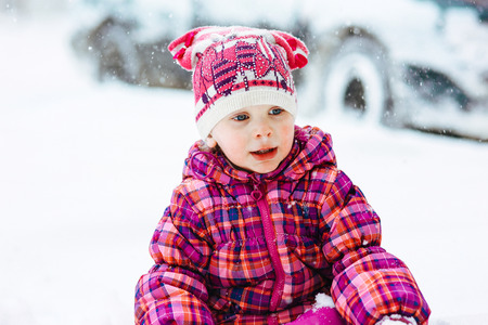 the girl in a lilac down-padded coat walks in snow weather on snowdriftsの写真素材