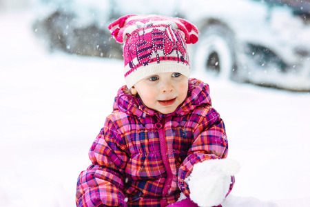 the girl in a lilac down-padded coat walks in snow weather on snowdriftsの写真素材