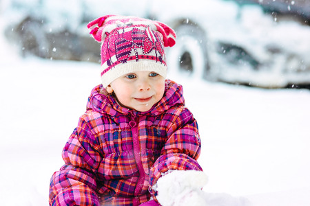 the girl in a lilac down-padded coat walks in snow weather on snowdriftsの写真素材