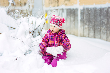 the girl in a lilac down-padded coat walks in snow weather on snowdriftsの写真素材