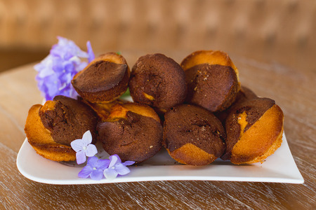 cakes on a white plate which costs on a table, lie flowers nearbyの写真素材