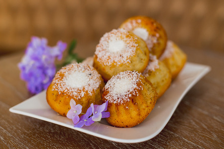 cakes on a white plate which costs on a table, lie flowers nearbyの写真素材