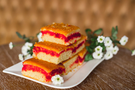 cake with a red stuffing on a white plate which costs on a table, lie flowers nearbyの写真素材
