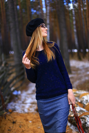 the girl wearing spectacles, in a blue sweater and a trouser skirt poses in the woodの写真素材