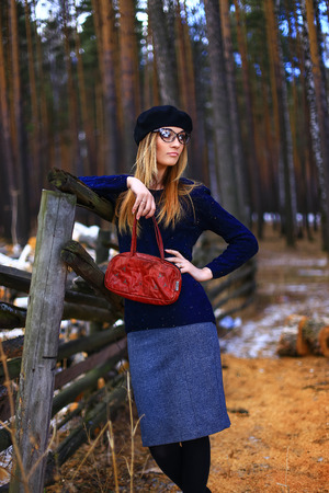 the girl wearing spectacles, in a blue sweater and a trouser skirt poses in the woodの写真素材