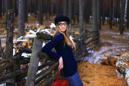 the girl wearing spectacles in a blue sweater and a trouser skirt poses in the woodの写真素材
