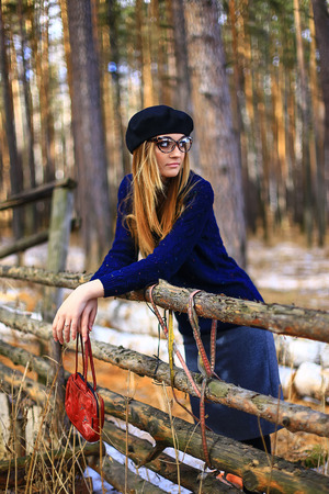 the girl wearing spectacles in a blue sweater and a trouser skirt poses in the woodの写真素材