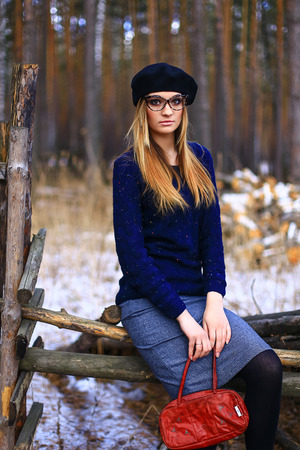 the girl wearing spectacles in a blue sweater and a trouser skirt poses in the woodの写真素材