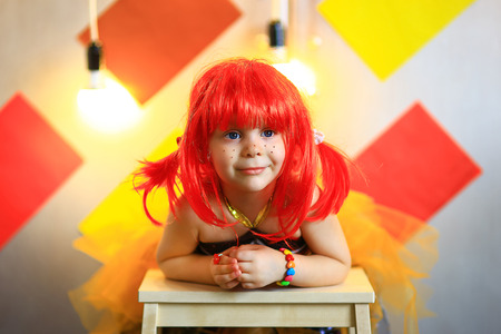the small the girl in a red wig with freckles poses on the cameraの写真素材