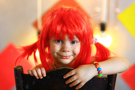the small the girl in a red wig with freckles poses on the cameraの写真素材