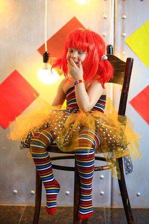 the small the girl in a red wig with freckles poses on the camera in striped stockingsの写真素材