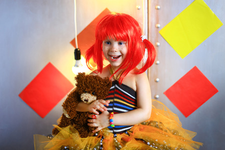 the small the girl in a red wig with freckles poses on the cameraの写真素材