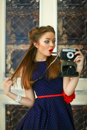 the girl in a dress in peas with red lipstick poses on the camera with the antiquarian cameraの写真素材