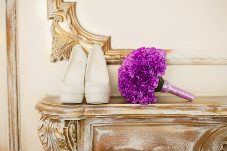 the violet bridal bouquet lies on a gold fireplace near white shoesの写真素材
