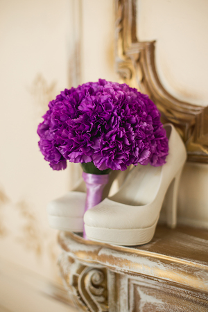 the violet bridal bouquet lies on a gold fireplace near white shoesの写真素材