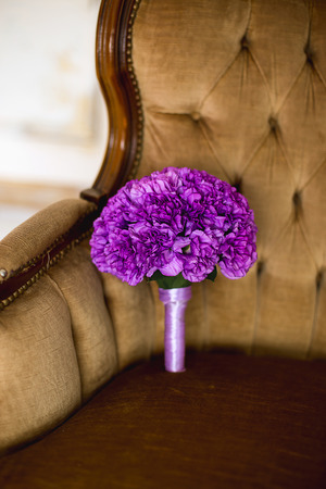the violet bridal bouquet lies on a starriny brown chairの写真素材